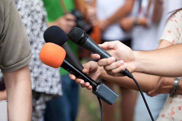 Close-up of reporters talking interview of man