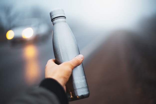 Photo close-up of reusable steel thermo bottle sprayed with water on wall of lush lava, aqua menthe and phantom blue of color.