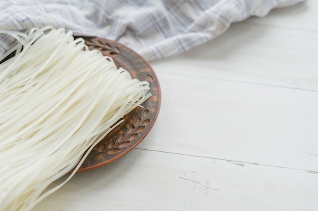 白い背景の上のテーブルクロスと丸皿の上の米春雨麺のクローズアップ