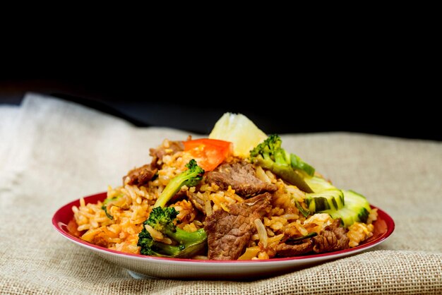 Photo close-up of rice with meat and broccoli served in plate against black background