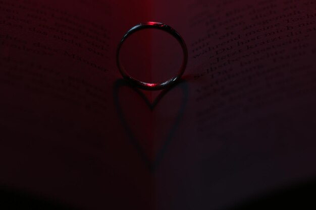 Photo close-up of ring forming heart shape shadow on book