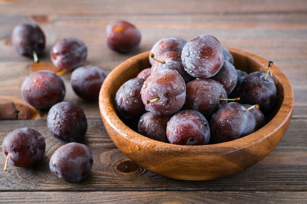 Close up on ripe blue plums in a wooden bowl