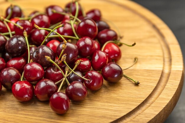 Close up ripe juicy red cherries on wooden plate. Organic farm cherries. Seasonal berries.