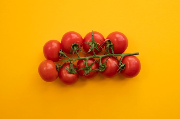 Close up ripe tomato on bright yellow background top view flat lay. Summer abstract background with tomato