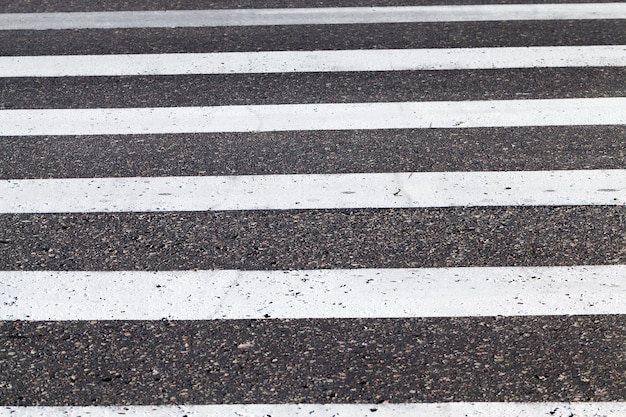 close-up of road marking is located on the roadway, white lines of a pedestrian crossing