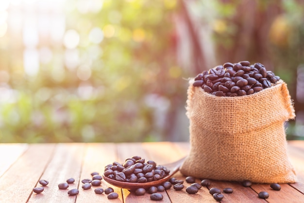 Close up roasted coffee beans in small sack on wooden table. 