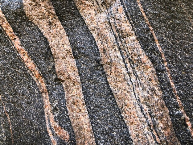 ピンクとグレーの縞模様の石の背景の岩のテクスチャ地質装飾の岩のクローズ アップ