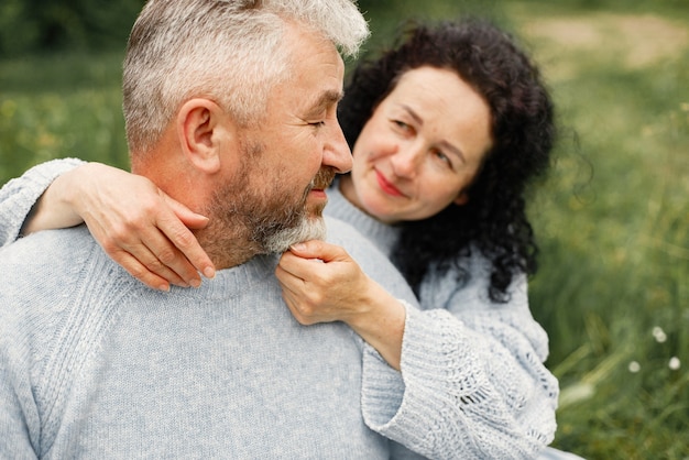 Close up romantic couple sitting in autumn park and hugging in daytime