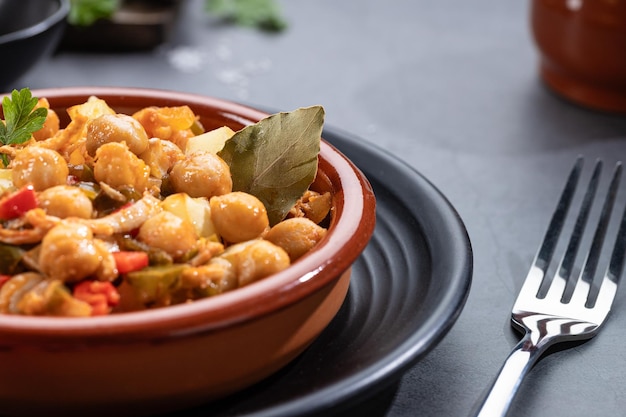 Photo close up ropa vieja typical canarian dish of chickpeas stew on earthenware casserole on dark base