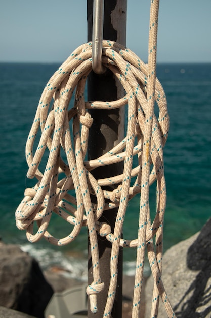 Foto close-up di una corda legata a un bollard dal mare contro il cielo
