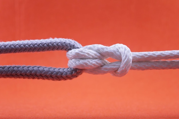 Foto close-up di una corda legata al metallo su uno sfondo arancione