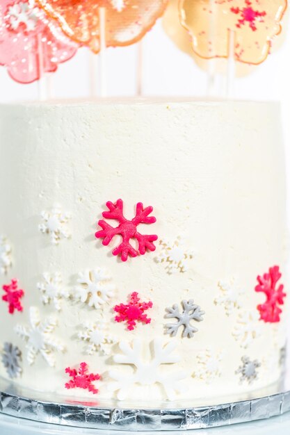 Close up of round cake with Italian buttercream frosting decorated with fondant snowflakes.