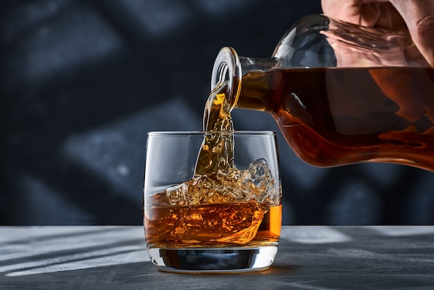 Photo close up of a round glass of whiskey with ice on the table