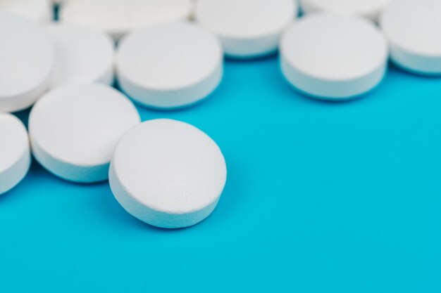 Close-up of round medical pills on blue background. Health care concept. copy space.