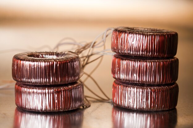 Close-up round transformer wrapped in wire lie on the table on top of each other