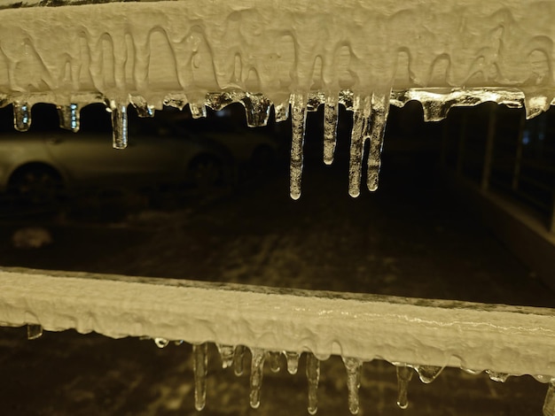 Primo piano su una fila di ghiaccioli appesi a un edificio in inverno con cooyspace concettuale del tempo, del clima e delle stagioni