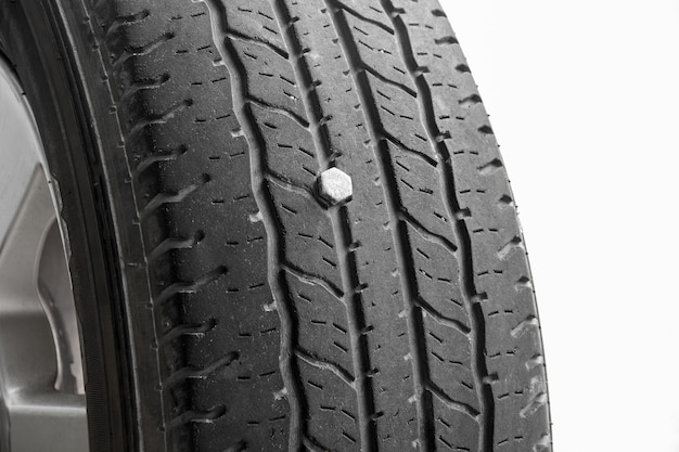 Close up of rubber tires leak automobile tire drilled with a metal screw nail on white background