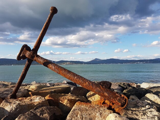 Photo close-up of rusty metal by sea against sky