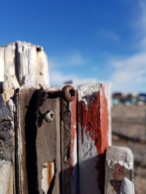 Close-up of rusty metal on wood against sky