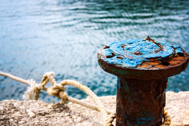 Close-up of rusty metallic bollard by sea