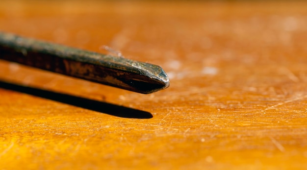 Close up of a rusty screwdriver on a brown table, selected focus