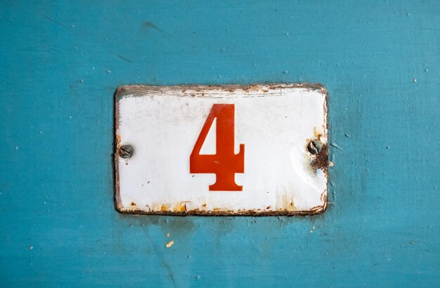 Photo close-up of rusty sign with number 4 on blue wall