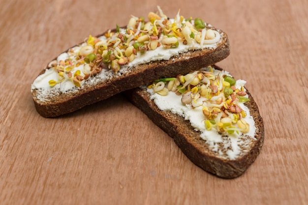 Close up of rye bread sandwiches with cream cheese and sprouted mung beans, walnut, sunflower and flax on wooden wall. vegan, raw food diet.