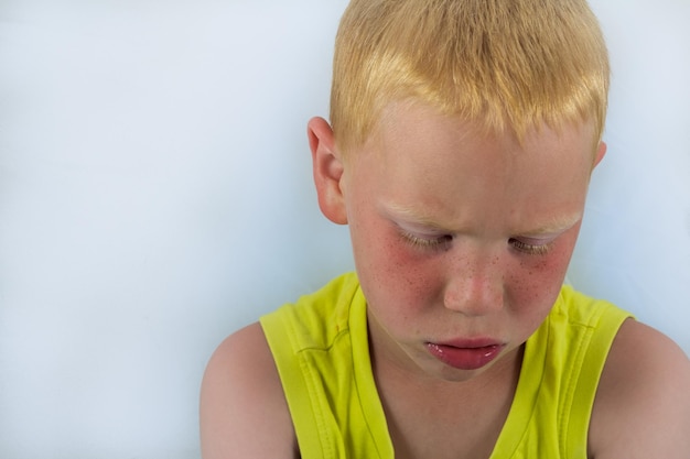 Foto close-up di un ragazzo triste contro un muro bianco