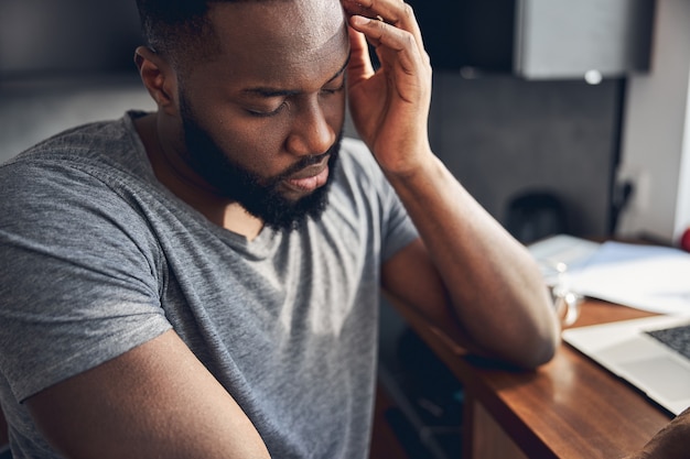 Photo close up of sad male that sitting at the table