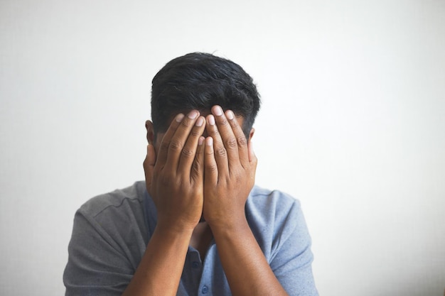 Photo close up of sad man covering face with hand