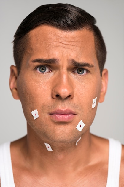 Photo close-up sad man having shaving cuts