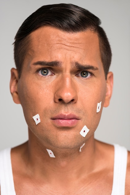 Close-up sad man having shaving cuts