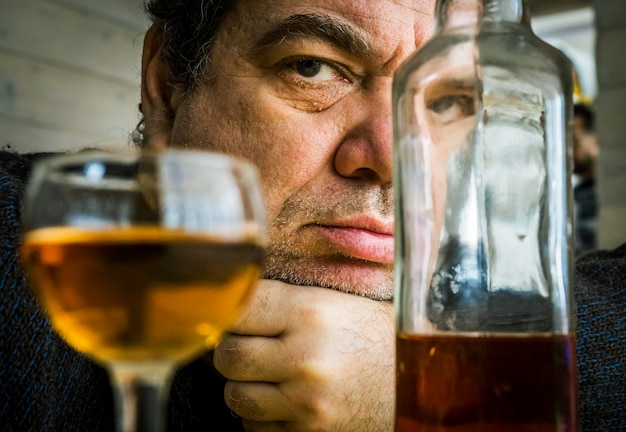 Foto close-up di un uomo triste con l'alcol sul tavolo