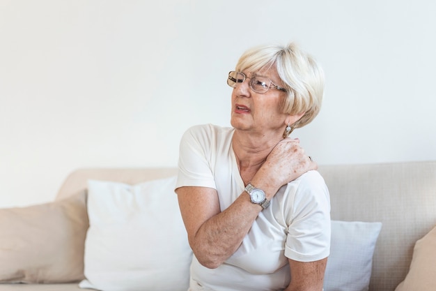 Close up of sad senior lady with neckache. Senior woman with chronic pain syndrome fibromyalgia suffering from acute neckaches. Senior woman suffering from neck pain