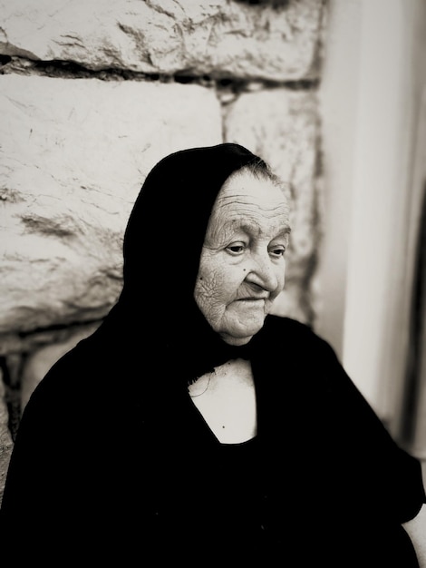 Foto close-up di una donna anziana triste che indossa il burka contro il muro