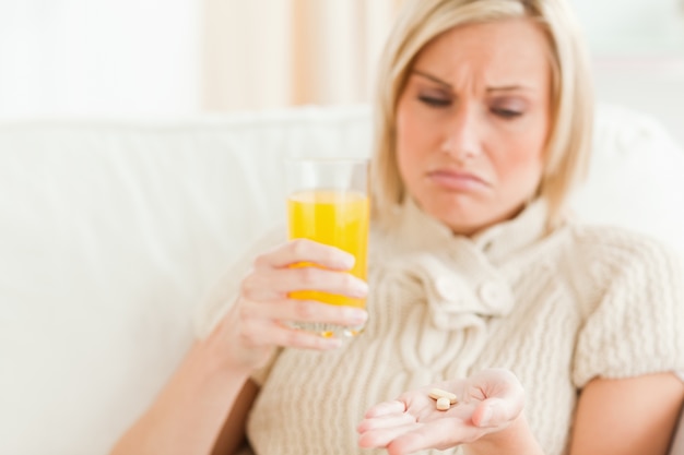 Close up of a sad woman showing pills