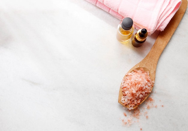 Photo close-up of salt in wooden spoon and massage oils over white background