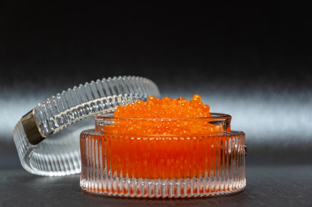 Close up of salted red caviar in a glassware on a black background