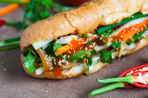 Photo close-up of sandwich with chili peppers on table