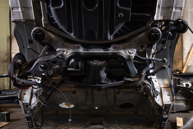 Close-up, sawn off part of an old car body: underbody, multi-link rear suspension, disc brakes, suspension arms, brake pipes in an old garage. Parsing jankyard