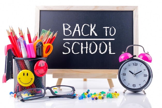 Close-up of school supplies with alarm clock against white background