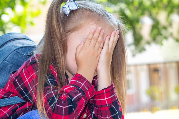 Photo close up on schoolgirl crying with her face in her hands