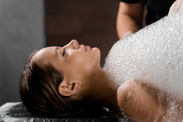 Close-up schuim peeling massage voor model in spa. Ontspanning in Turkse hamam.