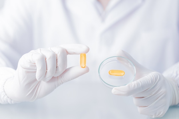 Close up Scientist hands putting in nitrile latex gloves holding Scientist holding capsule gel in labcoat wearing nitrile gloves, doing experiments in lab