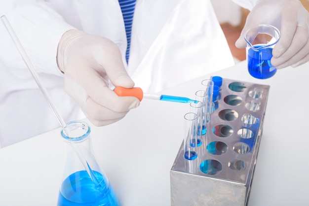 Close up of scientist testing and researching some blue liquid chemical