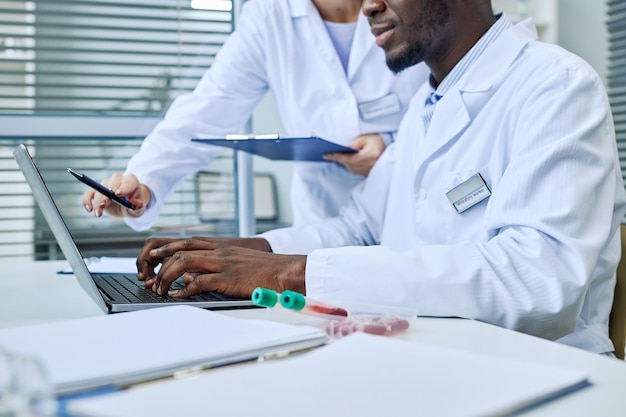 Close up of scientist using laptop while doing research in medical lab copy space