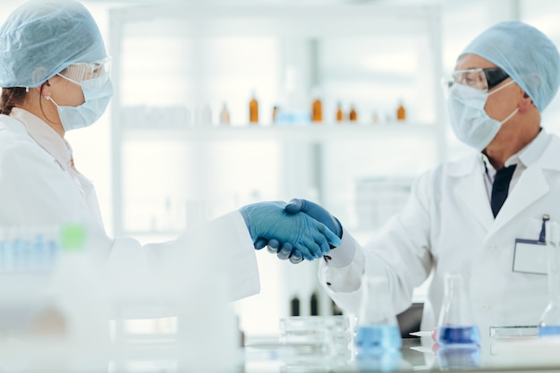 Close up. scientists colleagues shaking hands with each other. science and health.