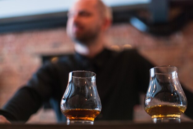 Photo close-up of scotch whiskey in glasses with man in background at bar