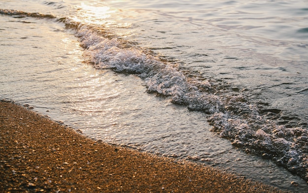 海の波の日没や日の出のビーチや砂の背景のクローズアップ