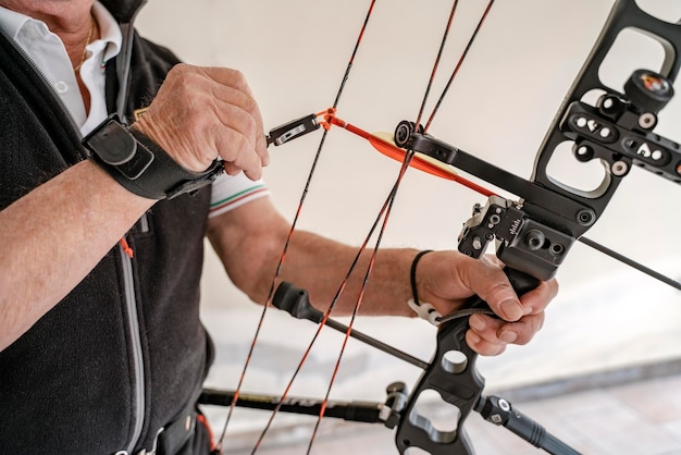 Close-up selectieve focus van professionele boogschutter die boog en pijl voorbereidt voor training